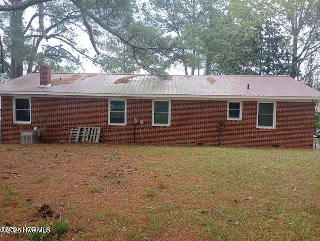 rear view of house featuring cooling unit and a yard