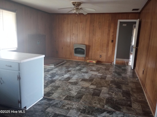 interior space featuring heating unit, ceiling fan, and wood walls