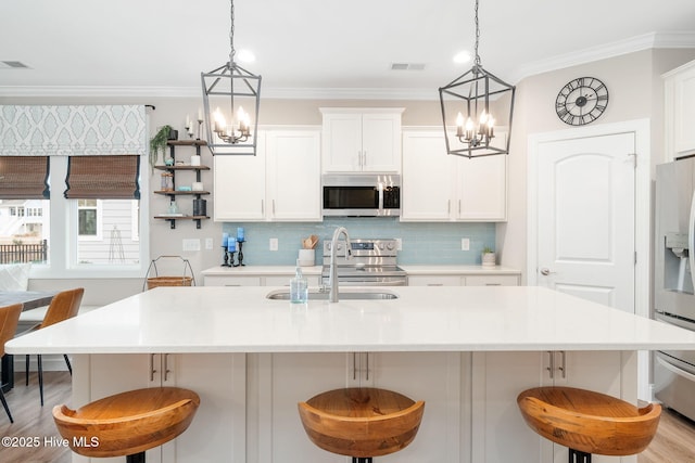 kitchen featuring a breakfast bar area, white cabinets, and appliances with stainless steel finishes