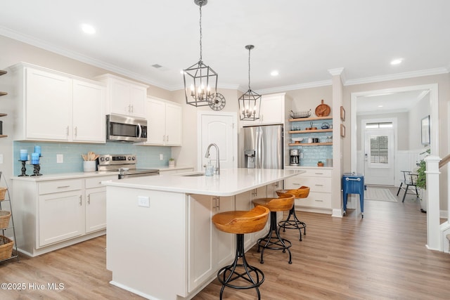 kitchen featuring white cabinetry, sink, stainless steel appliances, and an island with sink