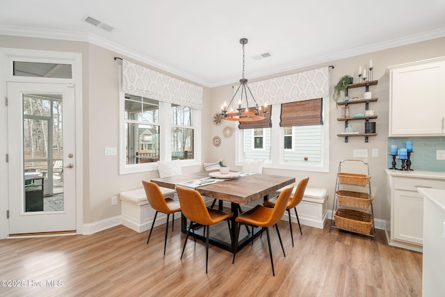 dining room with a notable chandelier, ornamental molding, and light hardwood / wood-style floors