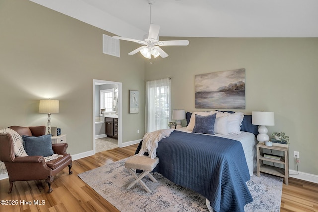 bedroom featuring light wood-style flooring, baseboards, connected bathroom, high vaulted ceiling, and a ceiling fan