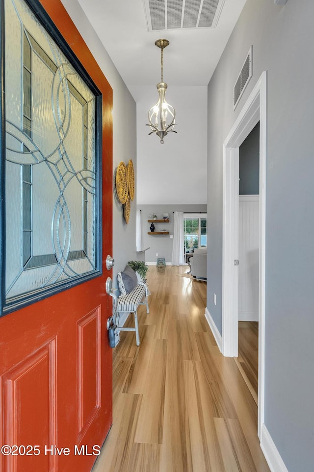 entryway featuring light wood-type flooring and a chandelier