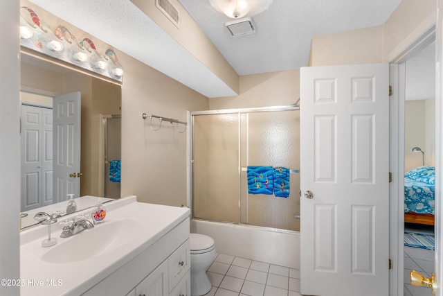 full bathroom with bath / shower combo with glass door, vanity, a textured ceiling, tile patterned floors, and toilet