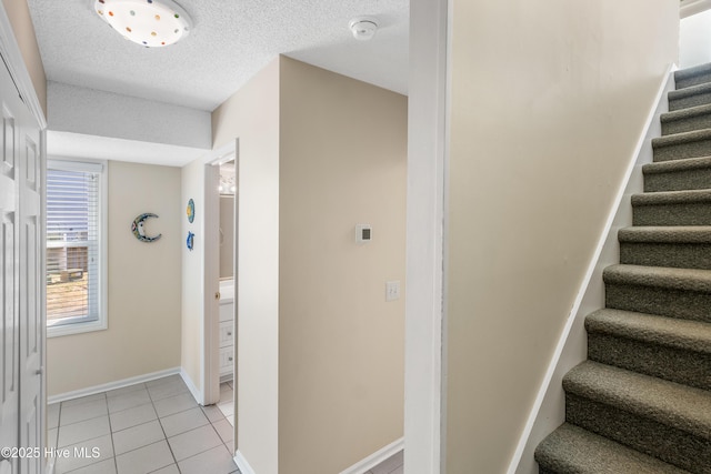 staircase featuring tile patterned flooring and a textured ceiling