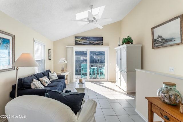 tiled living room featuring lofted ceiling with skylight, a textured ceiling, and ceiling fan