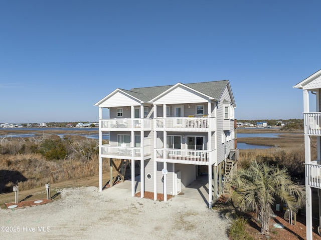 coastal home featuring a carport, a balcony, and a water view