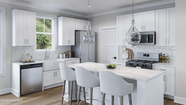 kitchen featuring pendant lighting, stainless steel appliances, white cabinets, and a kitchen island