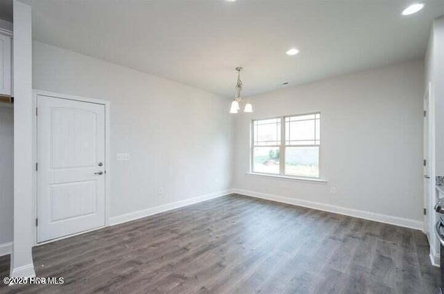 empty room with an inviting chandelier and dark hardwood / wood-style flooring