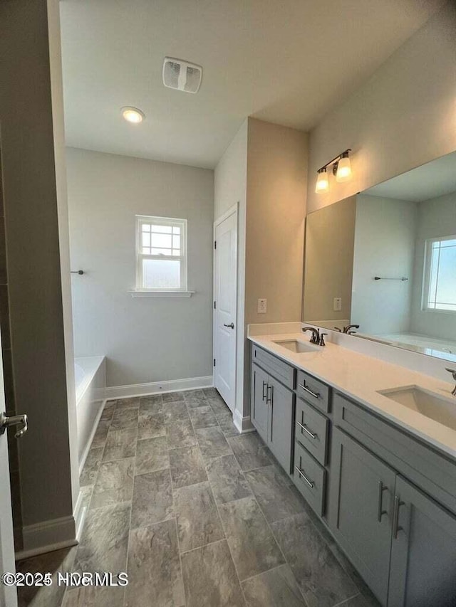1132 Coral Reef Dr, New Bern, NC 28560 - full bathroom with double vanity, a bathtub, healthy amount of natural light, and baseboards