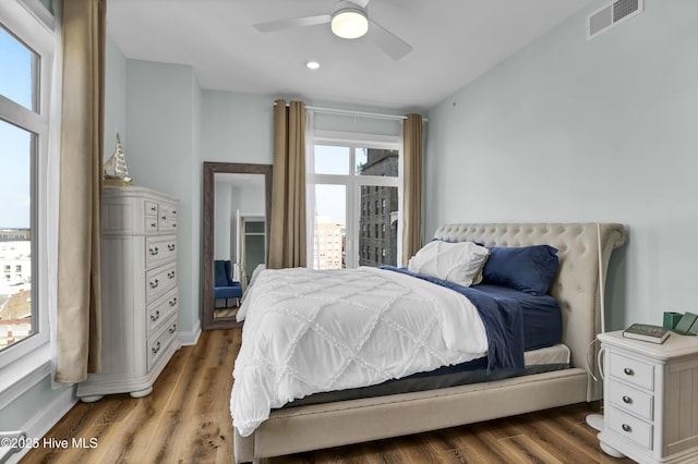 bedroom featuring ceiling fan, wood finished floors, visible vents, and baseboards