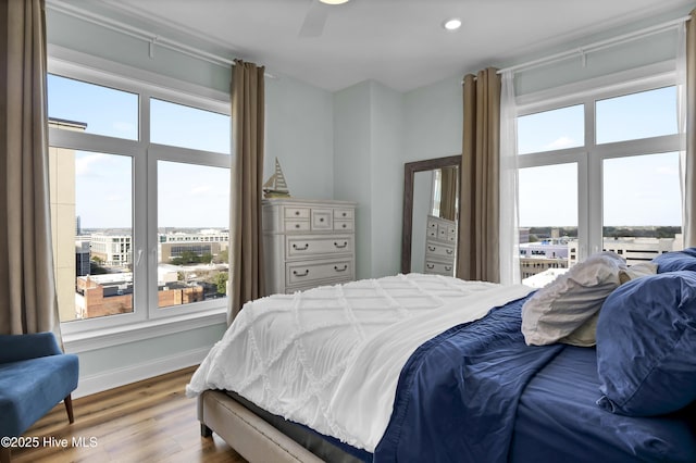 bedroom with recessed lighting, multiple windows, baseboards, and wood finished floors