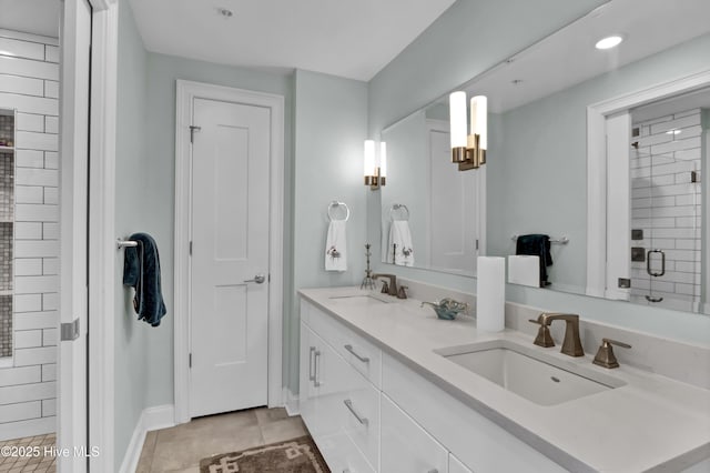 bathroom with a stall shower, double vanity, a sink, and tile patterned floors