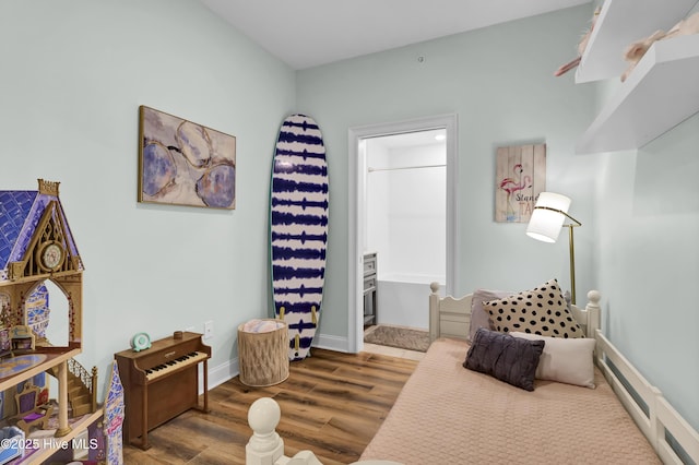 bedroom with connected bathroom, baseboards, and wood finished floors