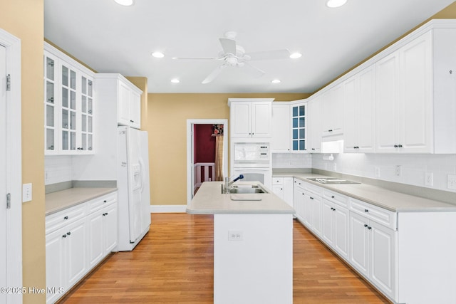 1824 Starfix Ter, Wilmington, NC 28405 - kitchen featuring white appliances, a ceiling fan, an island with sink, backsplash, and light wood-style flooring