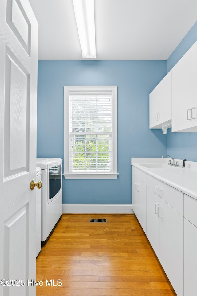 1824 Starfix Ter, Wilmington, NC 28405 - laundry area featuring separate washer and dryer, cabinet space, and light wood-style flooring