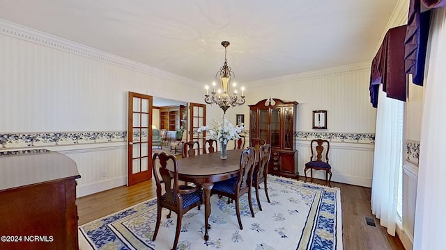 dining area featuring crown molding, a chandelier, and hardwood / wood-style floors