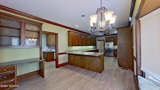 kitchen with pendant lighting, sink, a chandelier, ornamental molding, and stainless steel fridge with ice dispenser