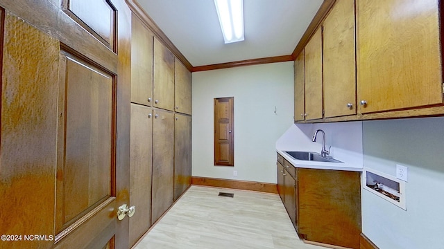 kitchen with crown molding, sink, and light hardwood / wood-style flooring