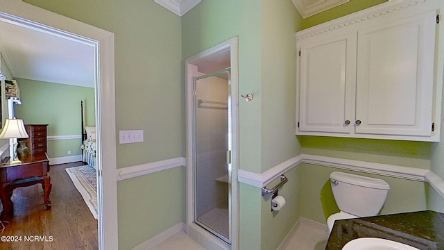 bathroom featuring hardwood / wood-style floors, vanity, ornamental molding, an enclosed shower, and toilet