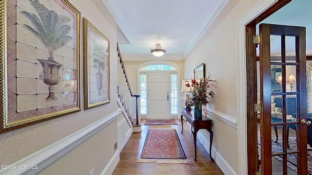 entrance foyer with ornamental molding and hardwood / wood-style floors