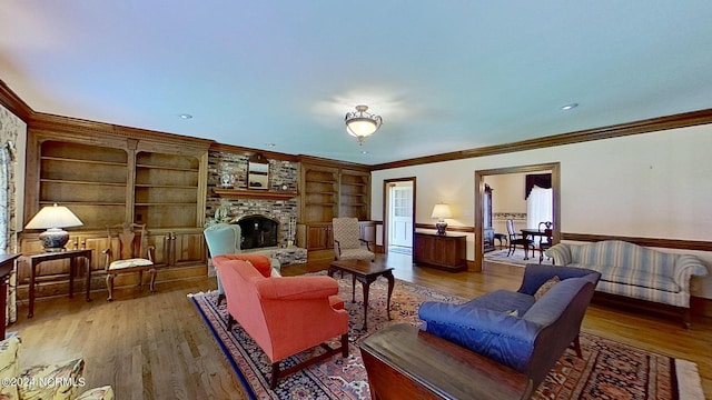 living room featuring crown molding, a stone fireplace, and hardwood / wood-style floors