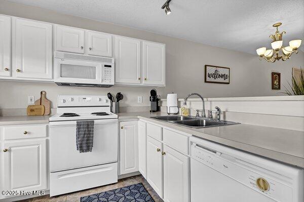 kitchen with sink, a notable chandelier, pendant lighting, white appliances, and white cabinets