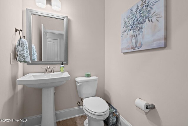 bathroom with hardwood / wood-style flooring, toilet, and sink