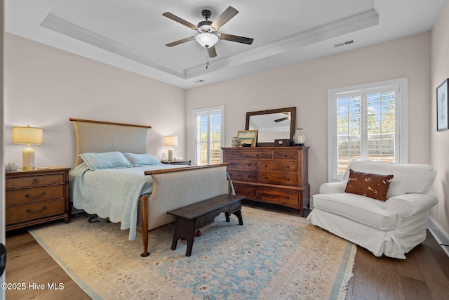 bedroom with a raised ceiling, ornamental molding, and light wood-type flooring