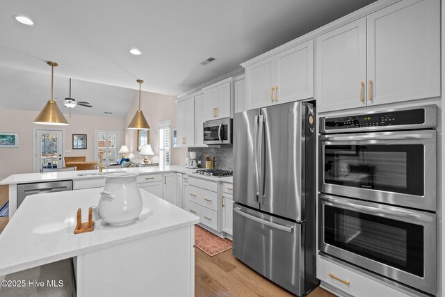 kitchen featuring pendant lighting, sink, stainless steel appliances, white cabinets, and kitchen peninsula