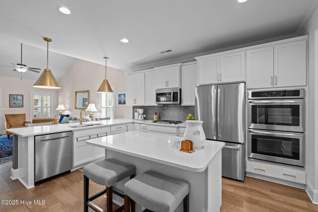 kitchen with appliances with stainless steel finishes, kitchen peninsula, sink, and white cabinets