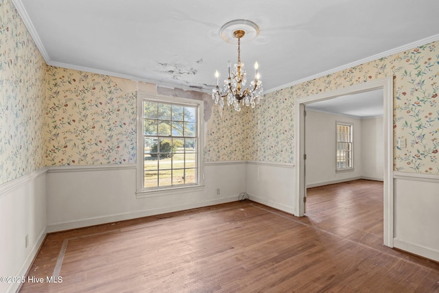 empty room featuring hardwood / wood-style flooring, crown molding, and a notable chandelier