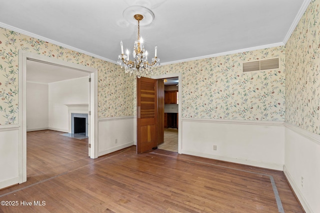 spare room featuring wood-type flooring, a notable chandelier, and ornamental molding