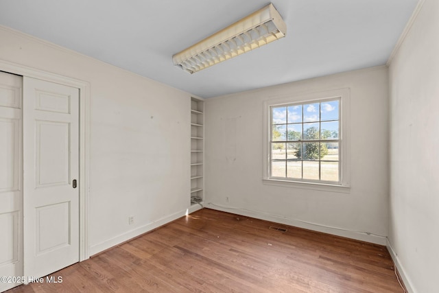 empty room with hardwood / wood-style flooring and built in shelves