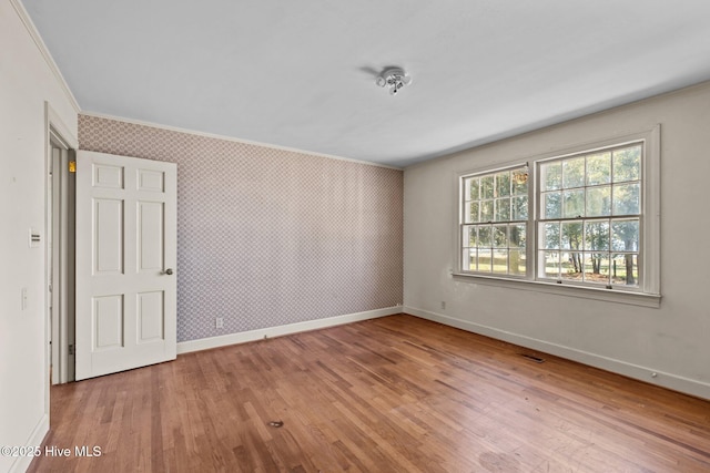 empty room with light hardwood / wood-style floors and crown molding