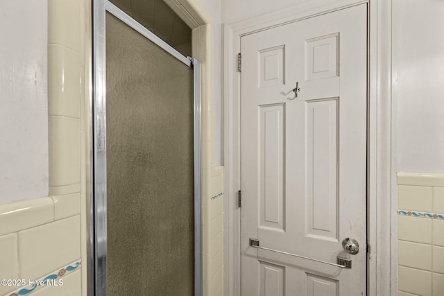 bathroom featuring a shower with shower door and tile walls