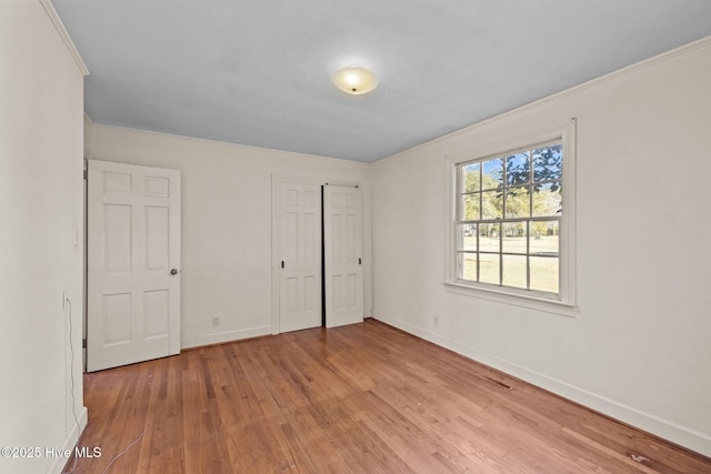 unfurnished bedroom featuring ornamental molding, a closet, and hardwood / wood-style floors