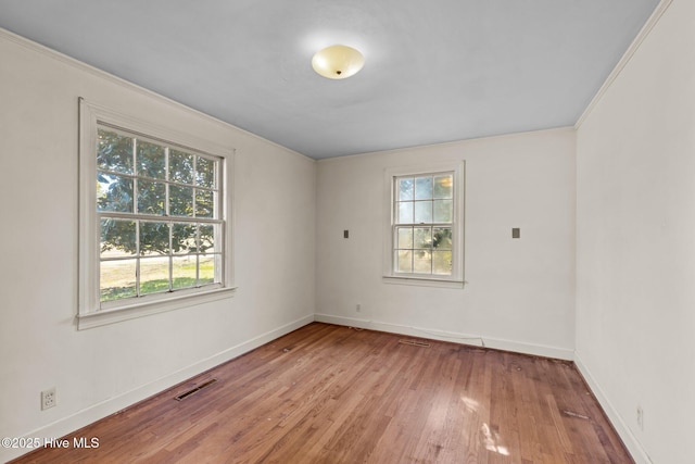 empty room with ornamental molding and light hardwood / wood-style floors