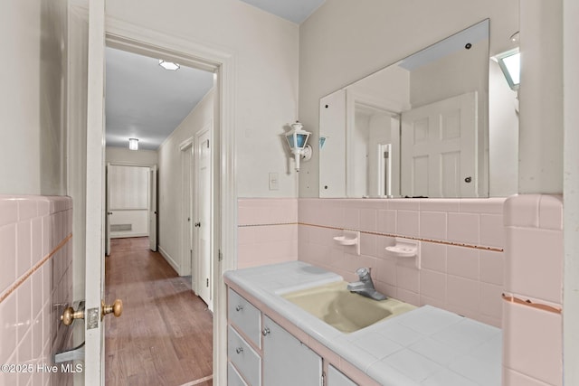 bathroom with hardwood / wood-style flooring, tile walls, and vanity