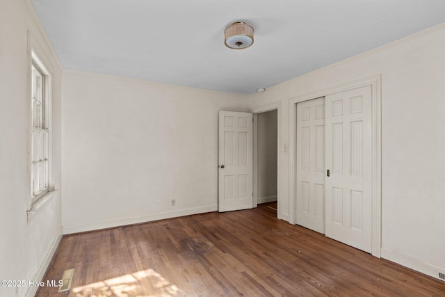 unfurnished bedroom with ornamental molding, a closet, and dark hardwood / wood-style flooring