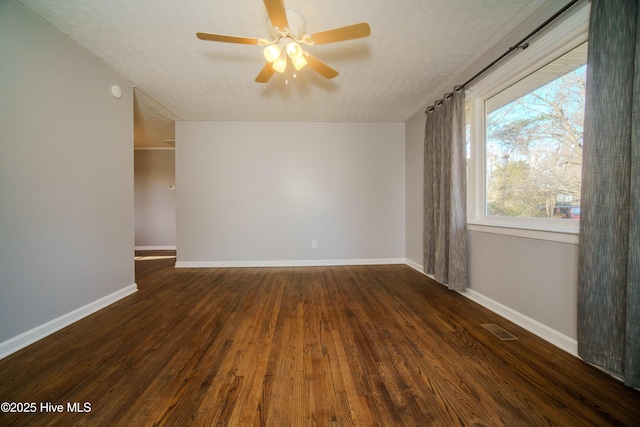 empty room featuring ceiling fan, dark wood-type flooring, and a textured ceiling