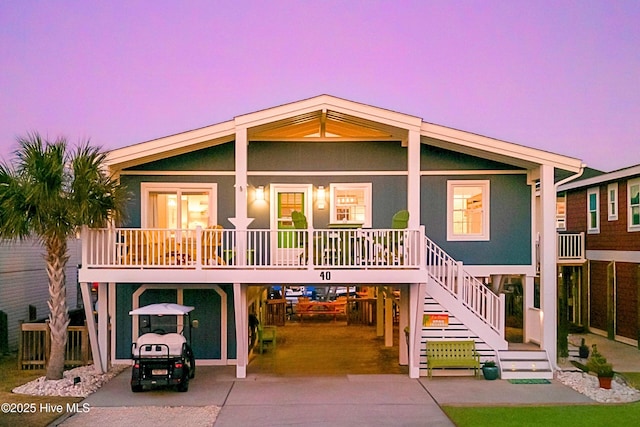 raised beach house with a carport, covered porch, driveway, and stairway