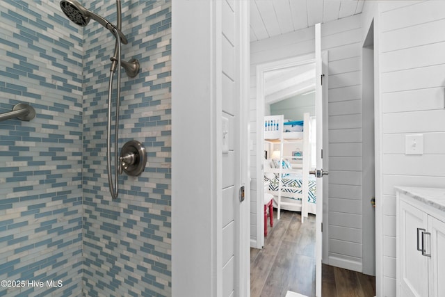 bathroom with lofted ceiling, tiled shower, vanity, and wood finished floors