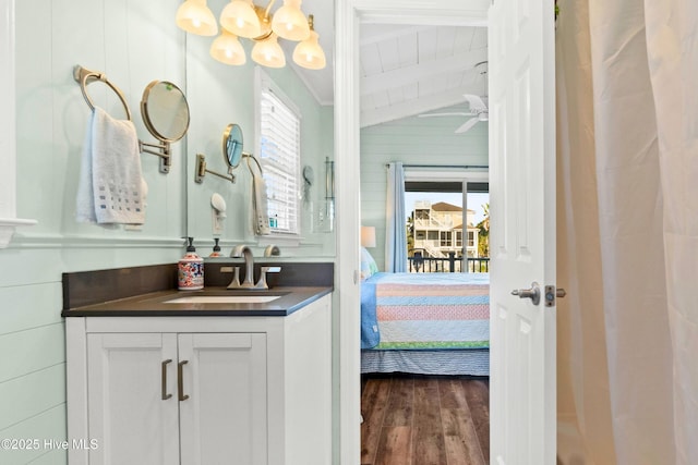 bathroom featuring a wealth of natural light, vaulted ceiling with beams, vanity, and wood finished floors