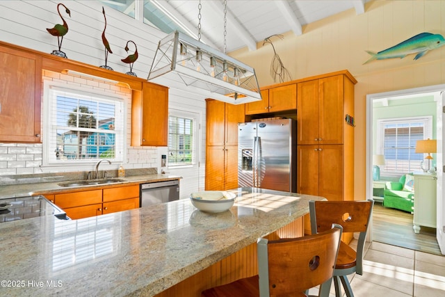 kitchen featuring a breakfast bar, a sink, appliances with stainless steel finishes, beam ceiling, and tasteful backsplash