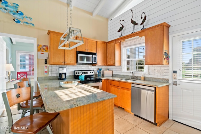 kitchen featuring a peninsula, decorative backsplash, stainless steel appliances, and a sink