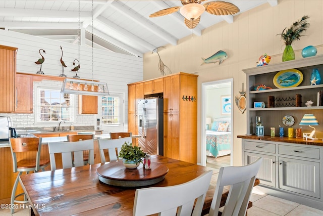 dining space featuring light tile patterned floors, high vaulted ceiling, wood walls, a ceiling fan, and beam ceiling