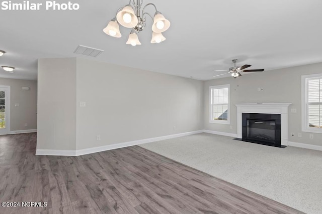 unfurnished living room featuring ceiling fan with notable chandelier, plenty of natural light, and hardwood / wood-style flooring