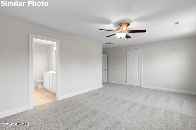 unfurnished bedroom featuring ceiling fan, ensuite bath, and light carpet