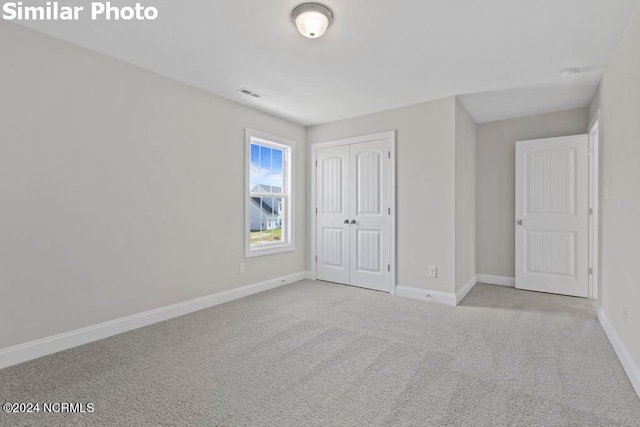 unfurnished bedroom featuring light carpet and a closet